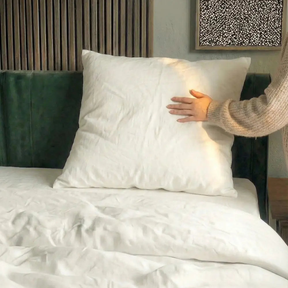 weibliche Hand berührt ein weißes Kopfkissen in einem modernen Schlafzimmer