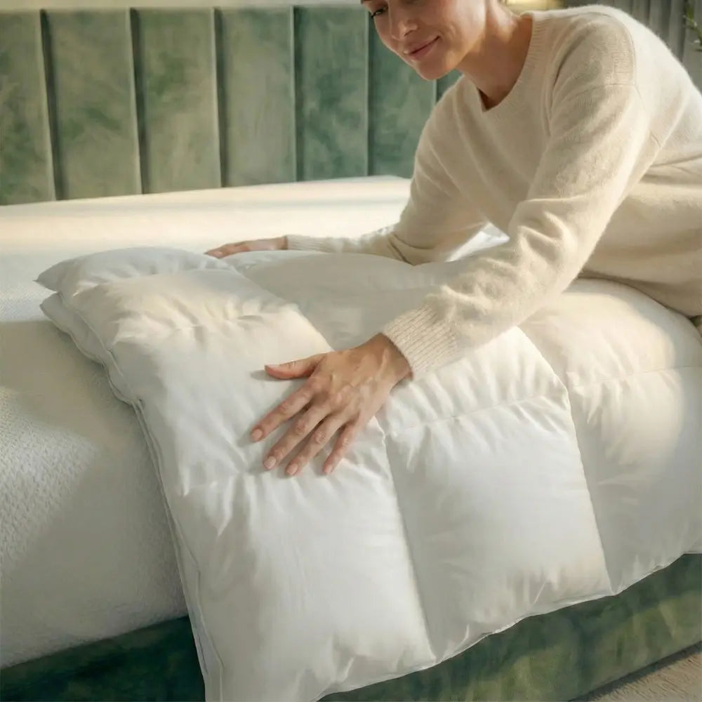 Frau streicht mit der Hand über die weiße Premium vegane Decke Polypearls auf dem Bett und zeigt die weiche, bauschige Oberfläche im Detail