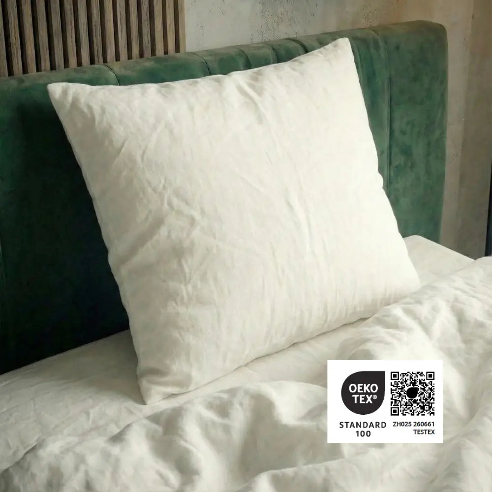 Essential veganes Faser-Kissen mit OEKO-TEX Standard 100 Zertifizierung auf Bett mit grünem Kopfteil