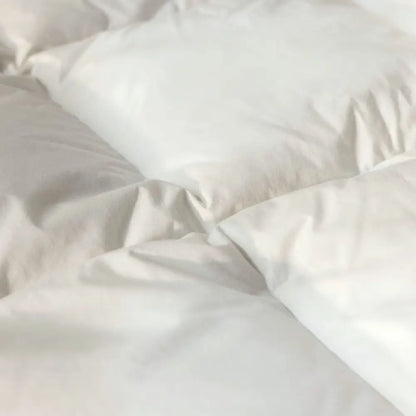 Detailaufnahme der weißen Superior Daunendecke mit weicher Oberfläche und fein gesteppter Struktur, zeigt das voluminöse Füllmaterial für hohen Schlafkomfort