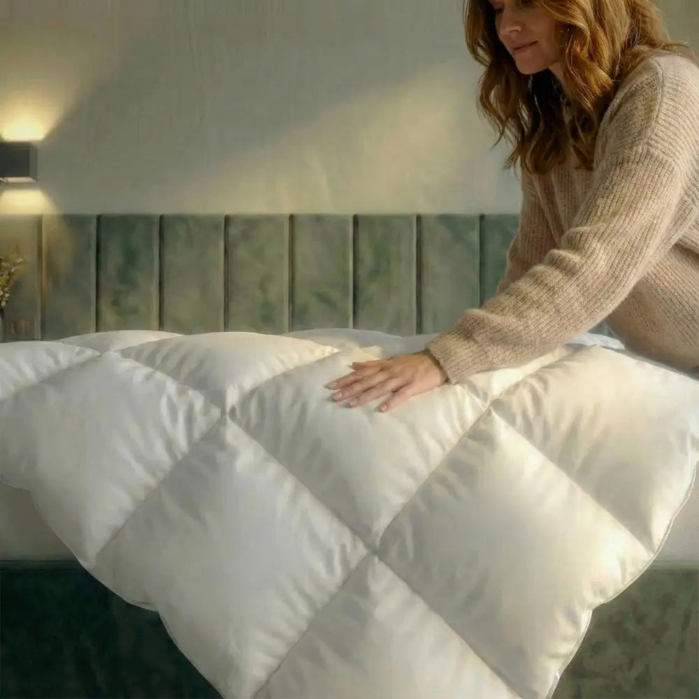 Hand streicht über die Premium Daunen- und Federdecke auf dem Bett, voluminöse Steppung zeigt weiche Oberfläche und hohen Kuschelkomfort