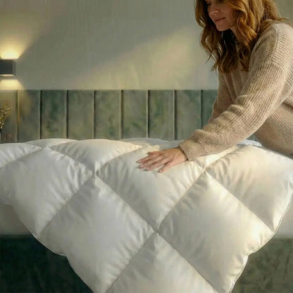 Hand streicht über die Premium Daunen- und Federdecke auf dem Bett, voluminöse Steppung zeigt weiche Oberfläche und hohen Kuschelkomfort