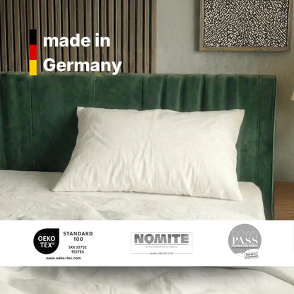 Weißes Essential Federkissen auf einem Bett mit Hinweis ‚made in Germany‘ und eingeblendeten Zertifikatslogos.