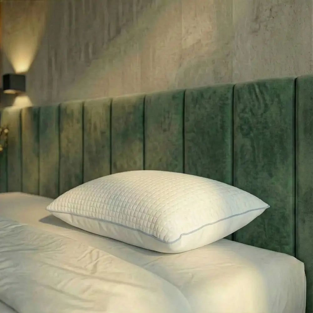 Weißes Essential Kühlkissen mit strukturierter Oberfläche liegt flach auf einem Bett vor grünem Kopfteil