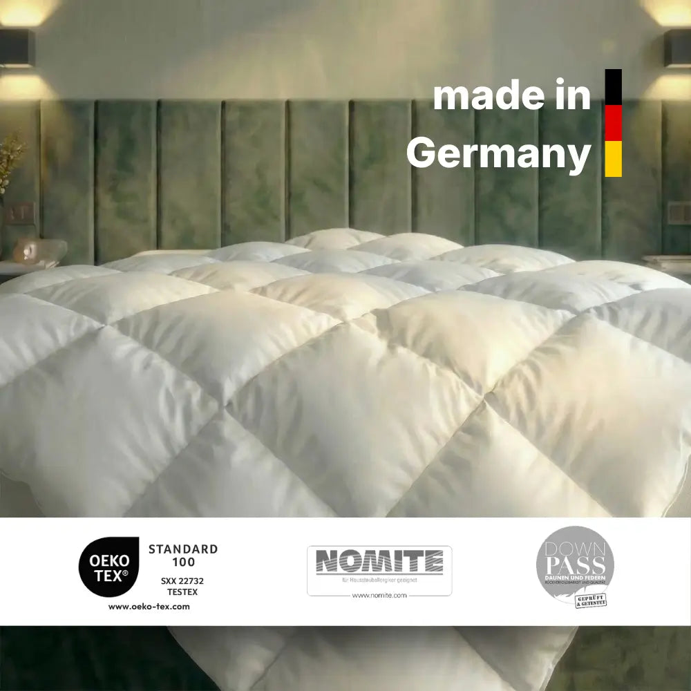 Weiße gesteppte Bettdecke auf modernem Bett mit grünem Kopfteil, gekennzeichnet mit ‚Made in Germany‘ sowie OEKO-TEX Standard 100, NOMITE und Downpass Zertifizierungen